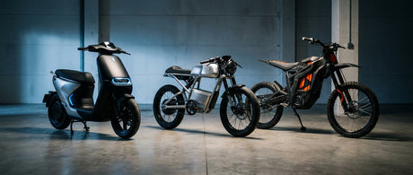 Three electric vehicles — an urban scooter, an e-moped, and a dirt bike — lined up side by side on a concrete surface under dramatic studio lighting, highlighting their distinct designs.
